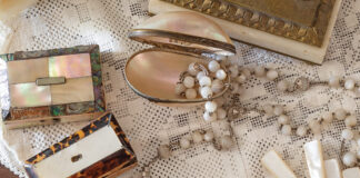 A mingling of mother-of-pearl trinkets is scattered atop a lace tablecloth.