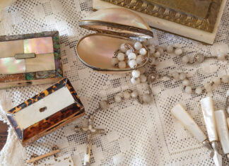 A mingling of mother-of-pearl trinkets is scattered atop a lace tablecloth.