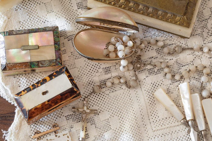 A mingling of mother-of-pearl trinkets is scattered atop a lace tablecloth.