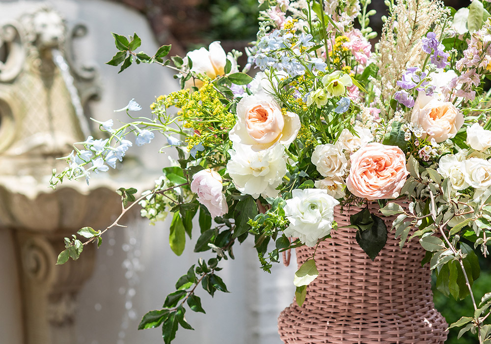 A large rattan vase holds a fragrant assortment of bright spring blooms.