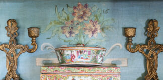 Rose medallion mantle pieces against a floral background, paired with antique candle sticks.