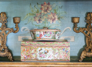 Rose medallion mantle pieces against a floral background, paired with antique candle sticks.
