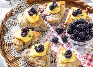 Blackberry-Thyme Scones nestle around a bowl of fresh blackberries. The pastries rest on a whicker tray, dappled in lace and red gingham.