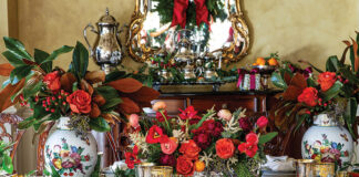A formal dining room finds itself the scene of vibrant Christmas splendor, including bright blossoms, magnolia leaves, and porcelain painted with the fruits of the season.