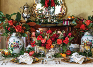 A formal dining room finds itself the scene of vibrant Christmas splendor, including bright blossoms, magnolia leaves, and porcelain painted with the fruits of the season.