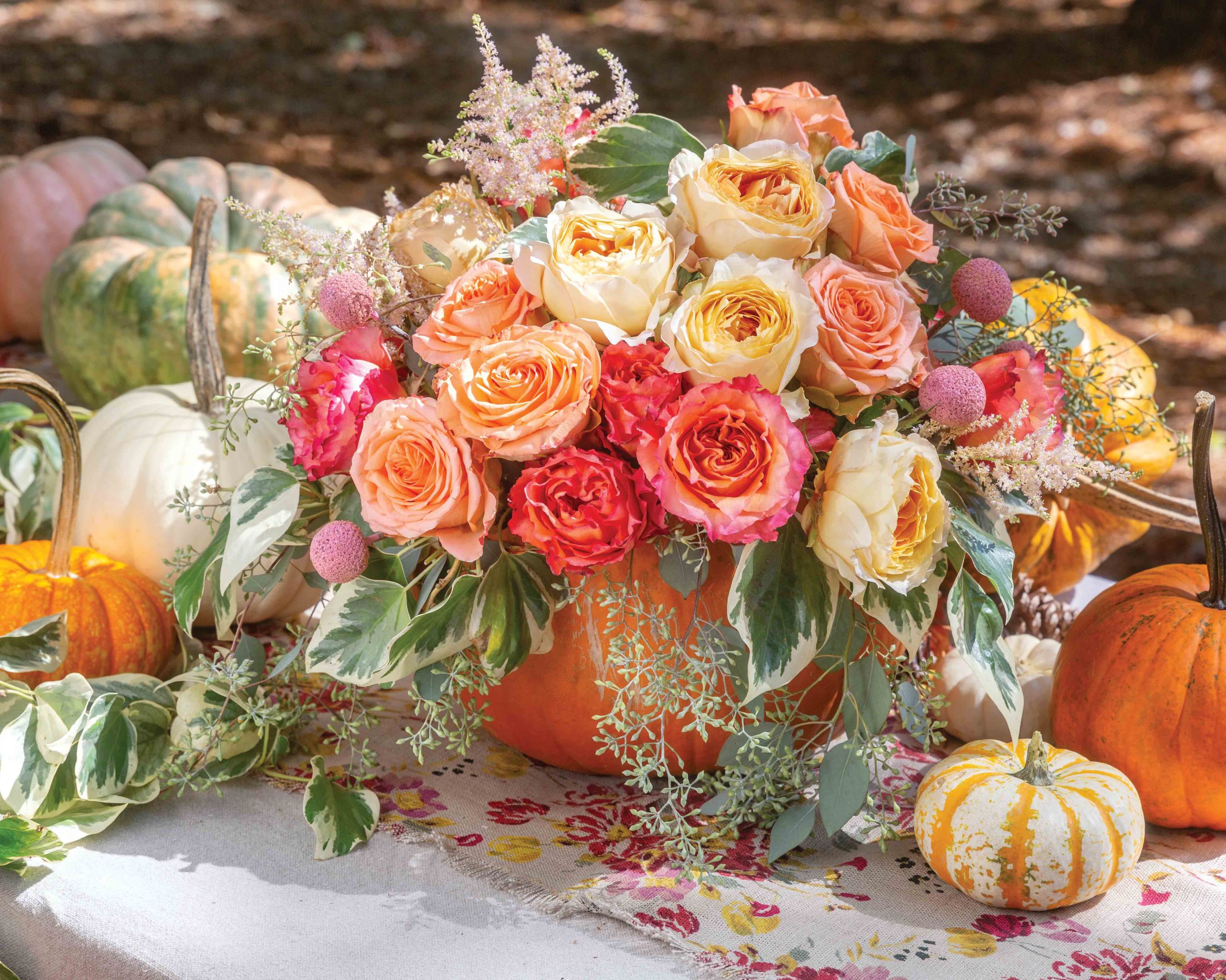 Pink and orange roses spill from a bright pumpkin in this centerpiece display.