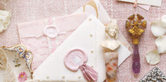A collection of crystalware is placed atop the table for cleaning, but the work is made into a lovely display with sprays of fresh pink peonies and curls of ribbon.