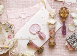 A collection of crystalware is placed atop the table for cleaning, but the work is made into a lovely display with sprays of fresh pink peonies and curls of ribbon.