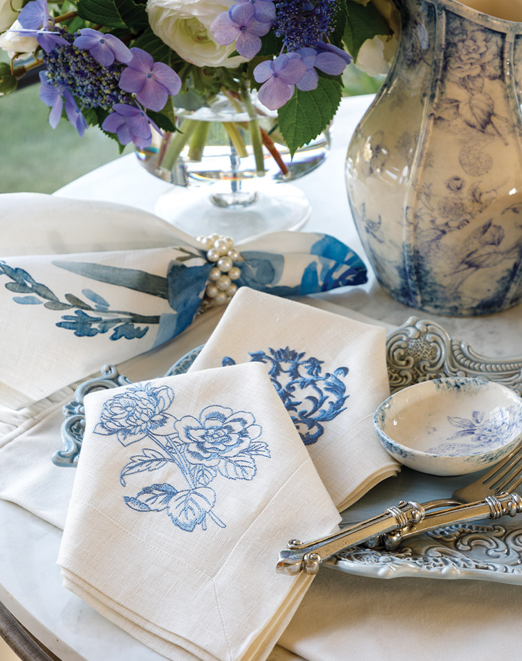 A mingling of blue-and-white pottery, flowers, and linens are arranged in this shop display.