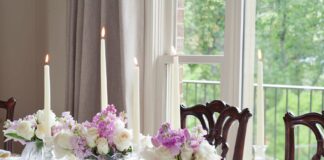 A tablescape with taper candles, a tea set, and purple flowers.