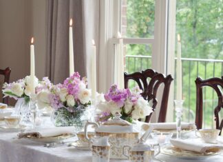 A tablescape with taper candles, a tea set, and purple flowers.