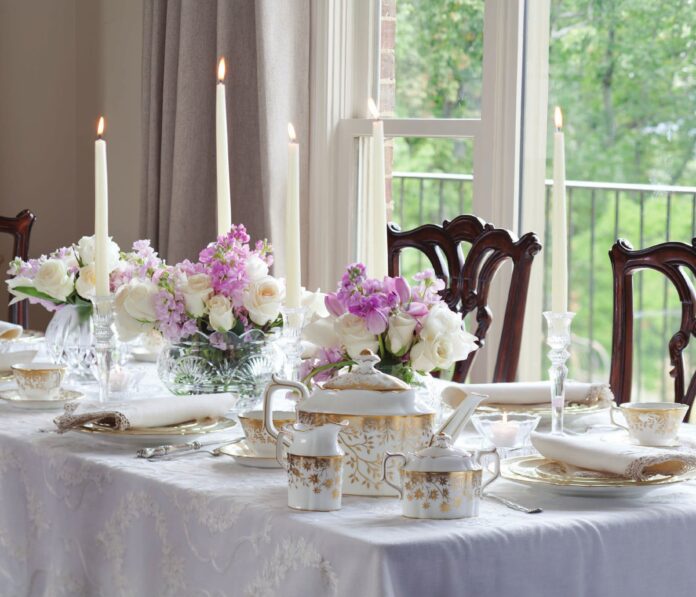 A tablescape with taper candles, a tea set, and purple flowers.