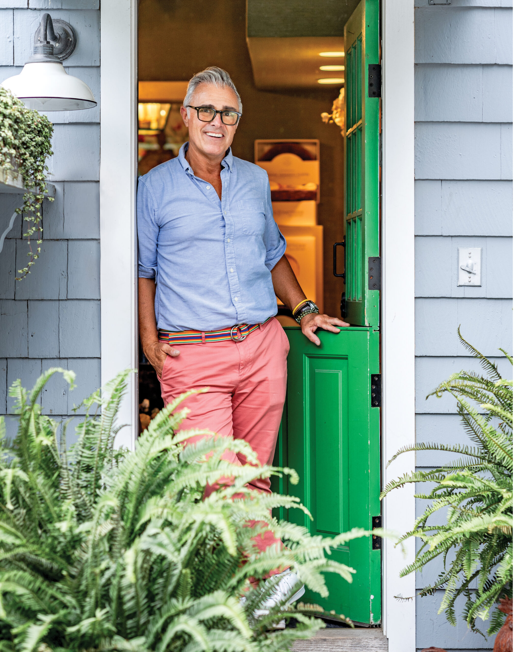 Man in blue shirt and pink pants standing in doorway