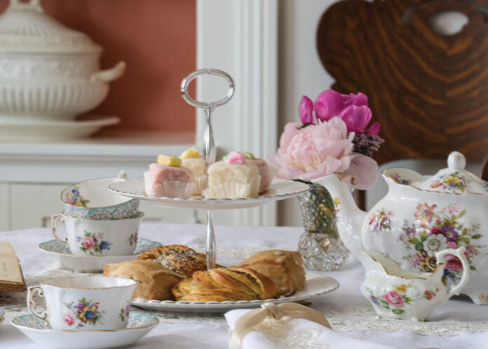Tea cups and tea pot with pastries on a table