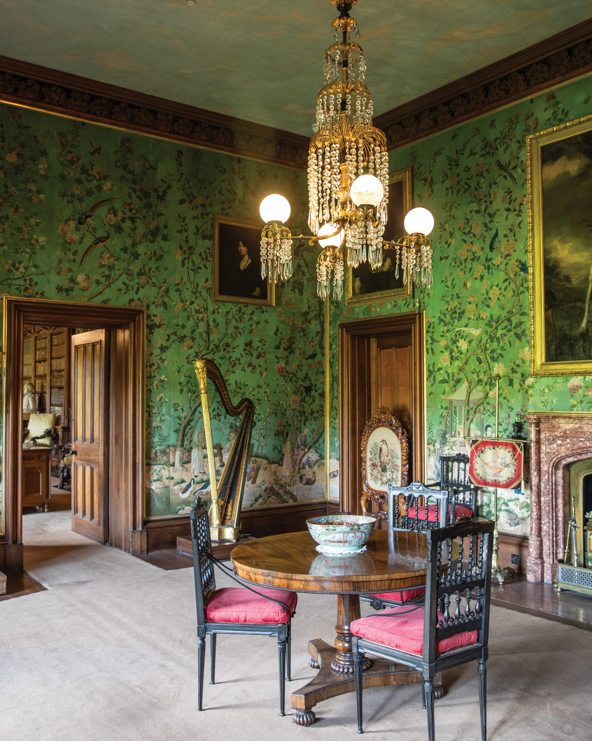 Room with green floral wallpaper, table and chairs, and gold harp