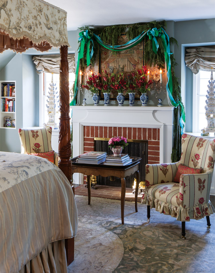 A fireplace draped with teal and green ribbons, with chinoiserie bases on the mantel, and greenery in a bedroom.