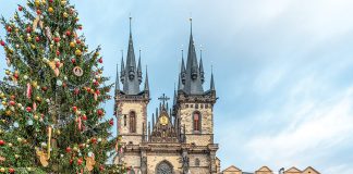 A massive outdoor Christmas tree stands outside the Church of Our Lady before Tyn, the spires of which rise above the square.