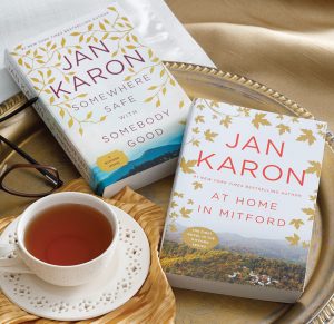 At Home in Mitford and Somewhere Safe with Somebody Good by Jan Karon side-by-side on a tracy with a cup of tea.