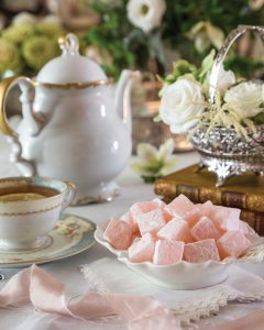 A dish of Turkish Delight sits beside a teacup and teapot, awaiting indulgence.