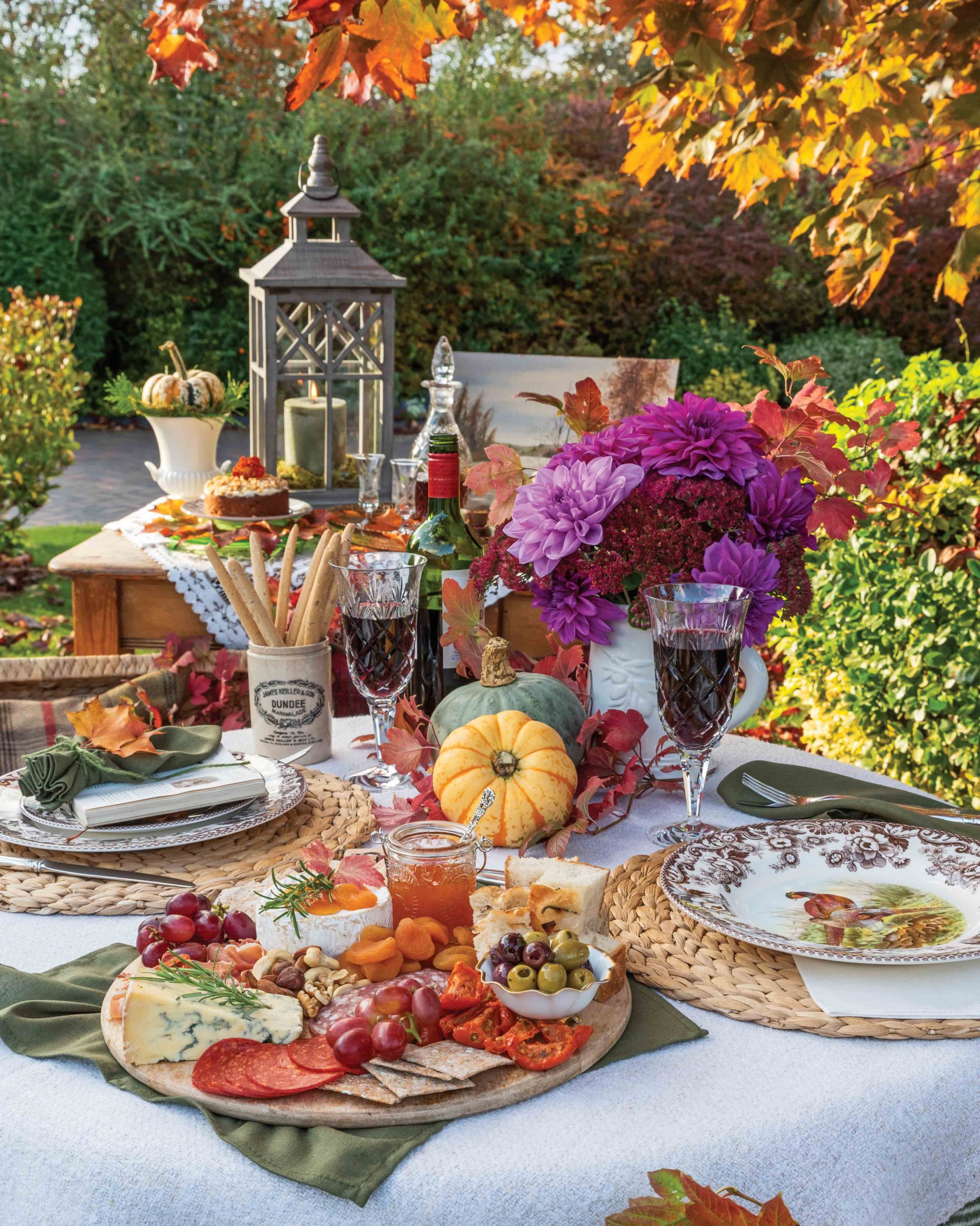 The table is set with charcuterie, wine, and decorative pumpkins and flowers.