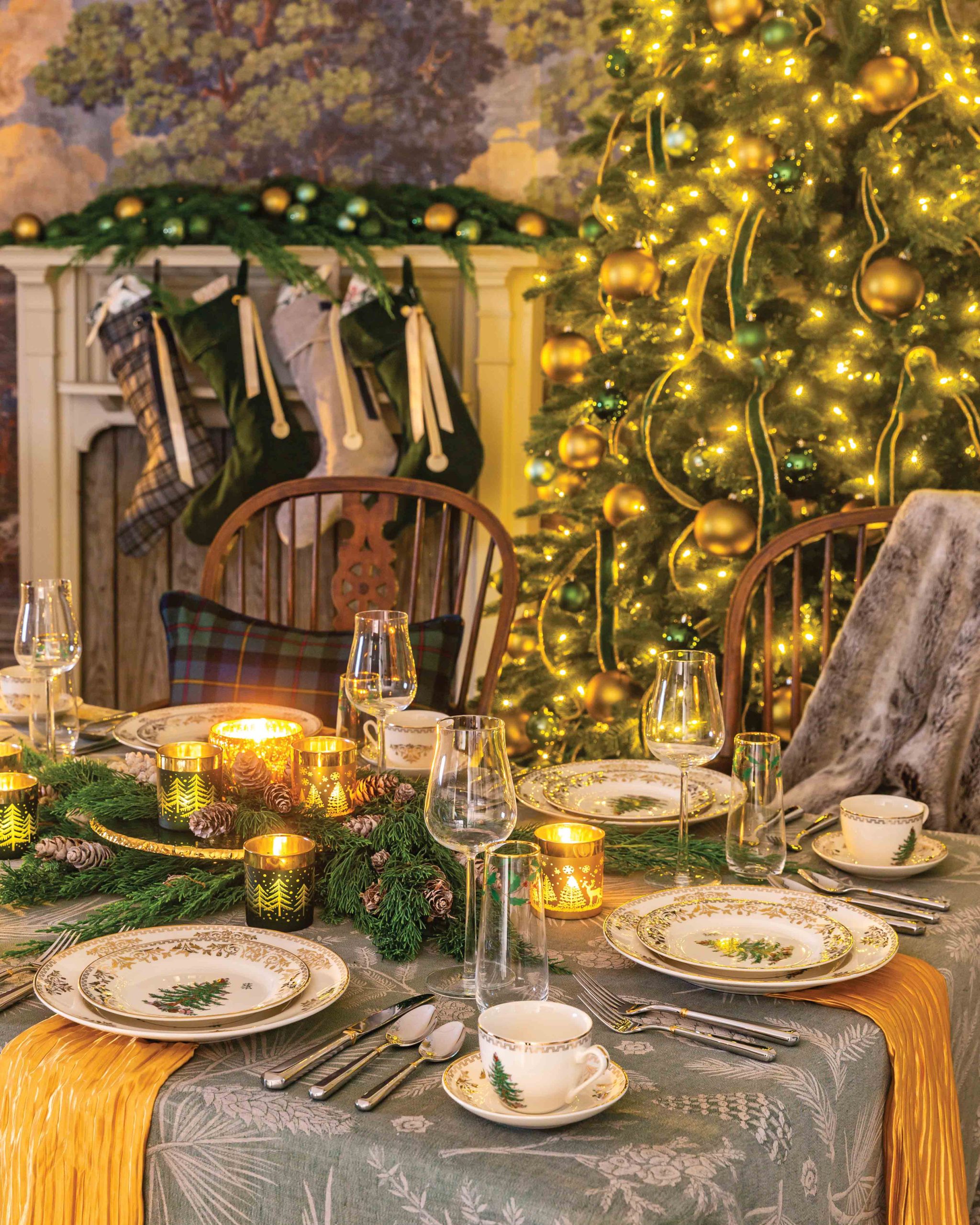 Glorious green and gold adorn this glowing table setting, where elegant tableware, candles, and evergreen boughs add details of Yuletide splendor.
