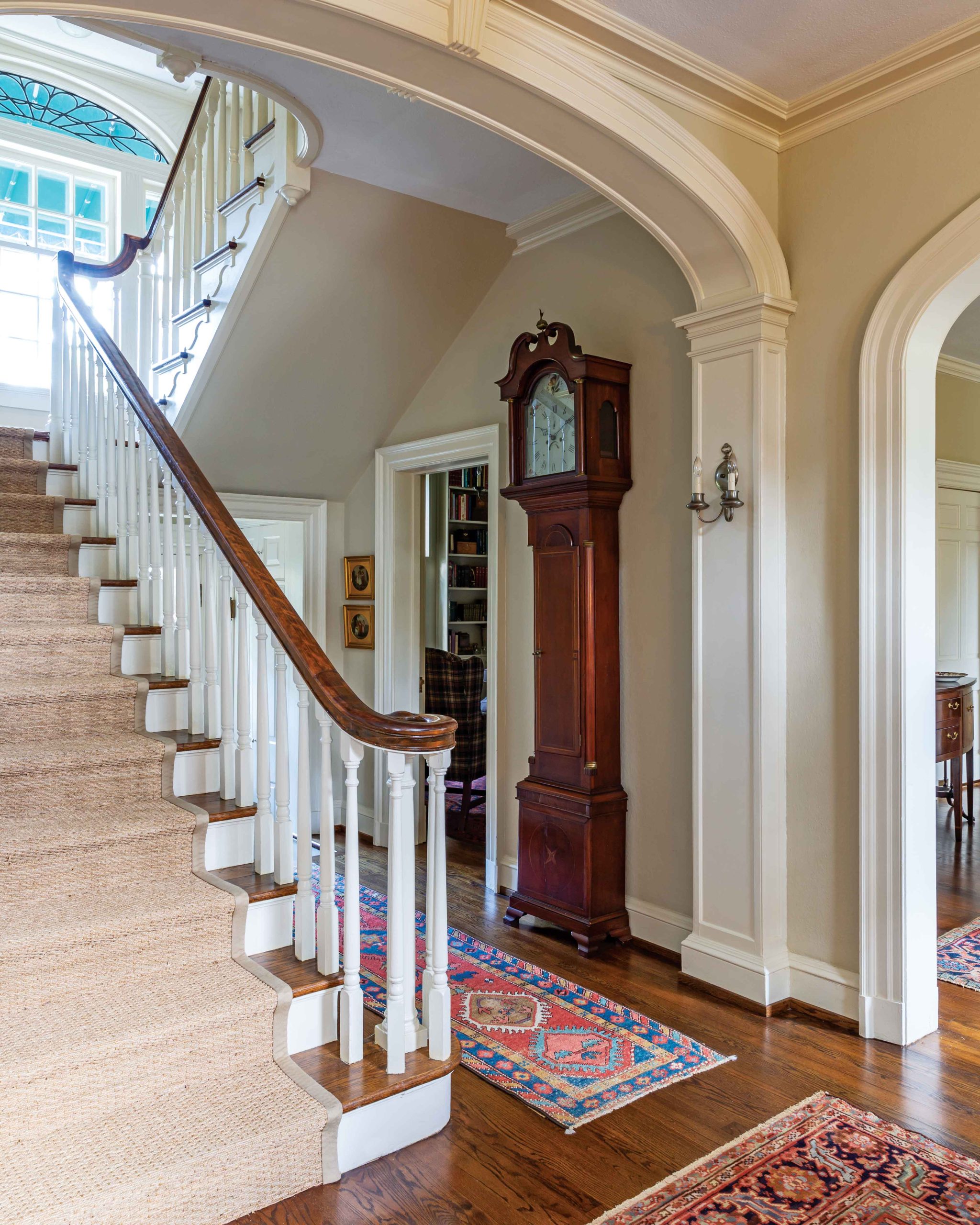 The entryway of this home includes an elegant staircase and grandfather clock.