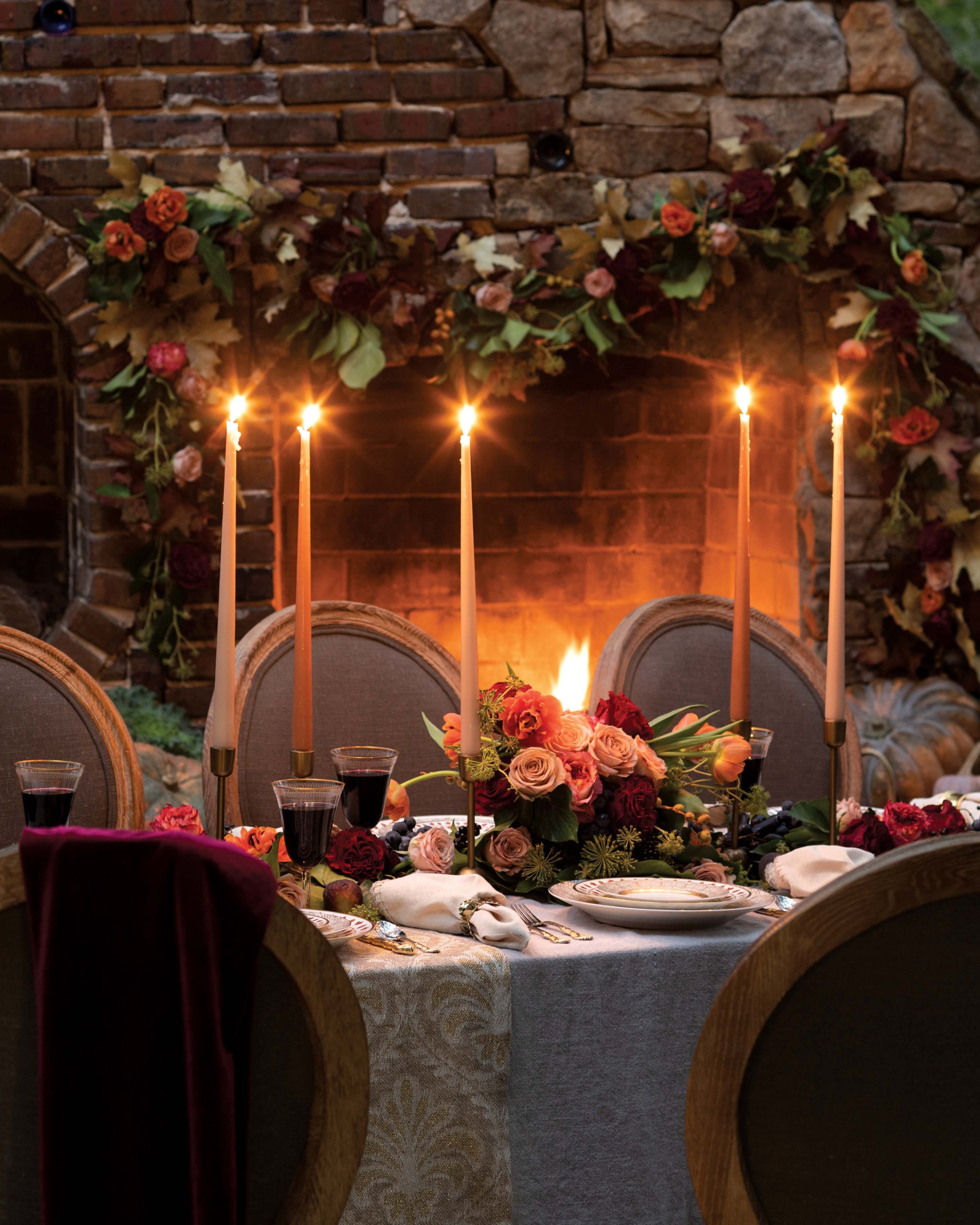Candles light the way at this table for a romantic feast, where deep red wine and equally brilliantly hued roses mingle among gilt accents and fine porcelain settings.