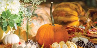 Decorating with Fall's Floral Bounty: Orange and white pumpkins, some cut into votive candle holders, adorn the table.
