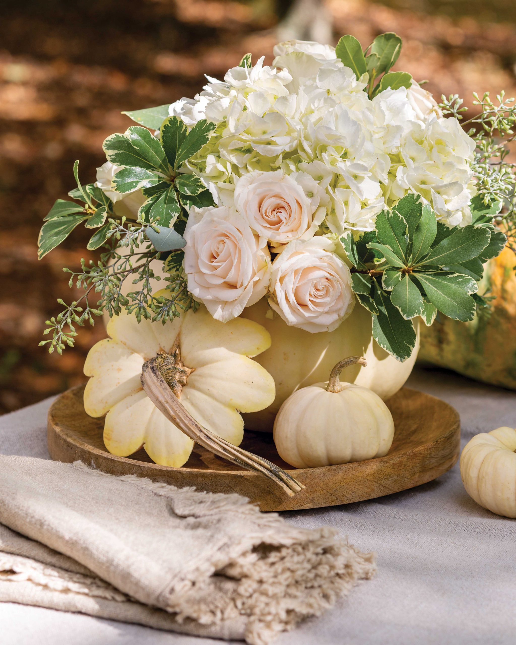 A vignette of white pumpkins and pale pink roses is accented by greenery.