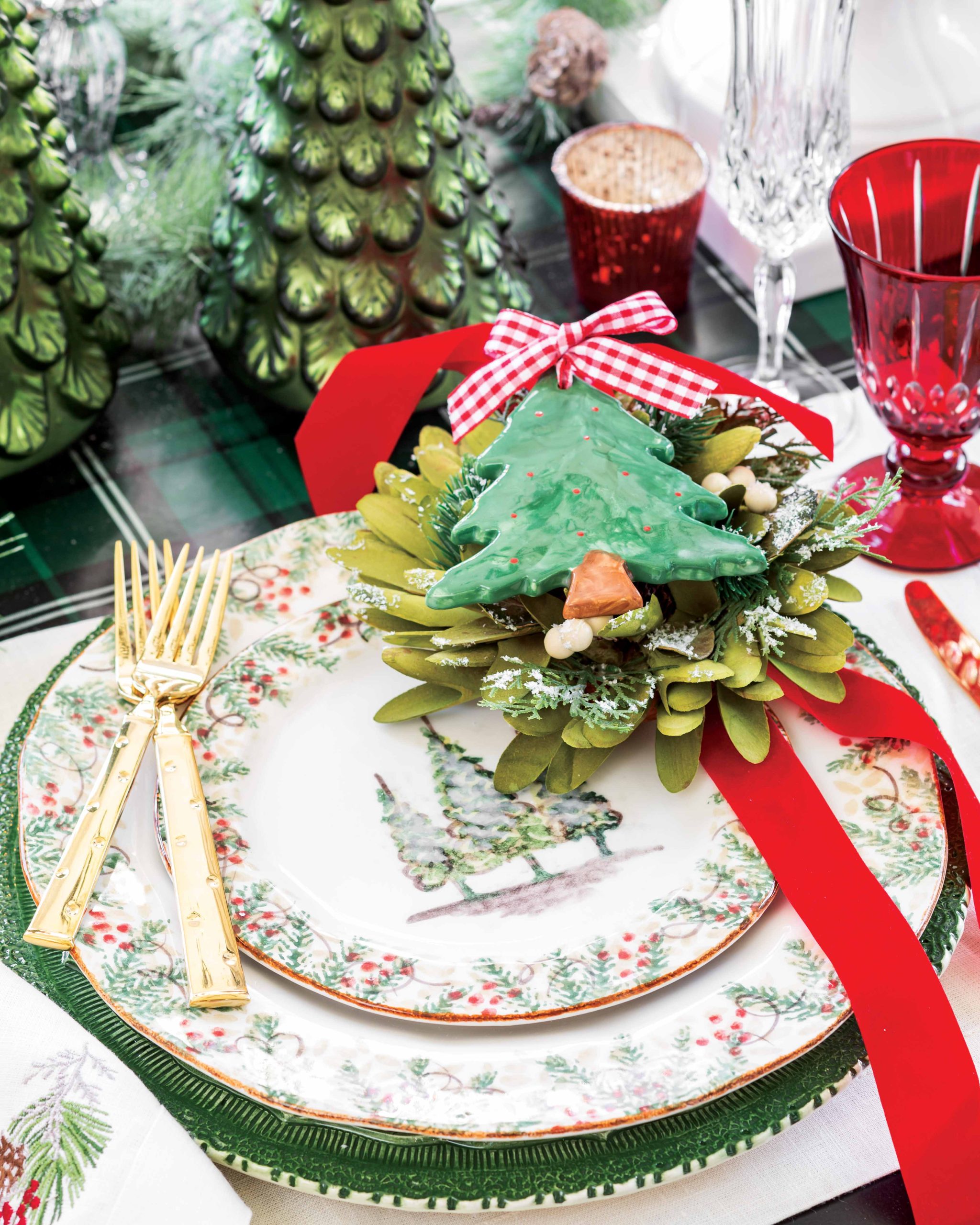 An Arte Italica place setting in the Natale pattern looks even more festive with gold flatware and an embroidered napkin from Crown Linen Designs.