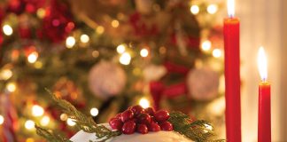 The focal point of a Christmas scene is panettone topped with homemade glaze, bright red berries, and sprigs of greenery.