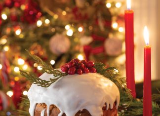 The focal point of a Christmas scene is panettone topped with homemade glaze, bright red berries, and sprigs of greenery.