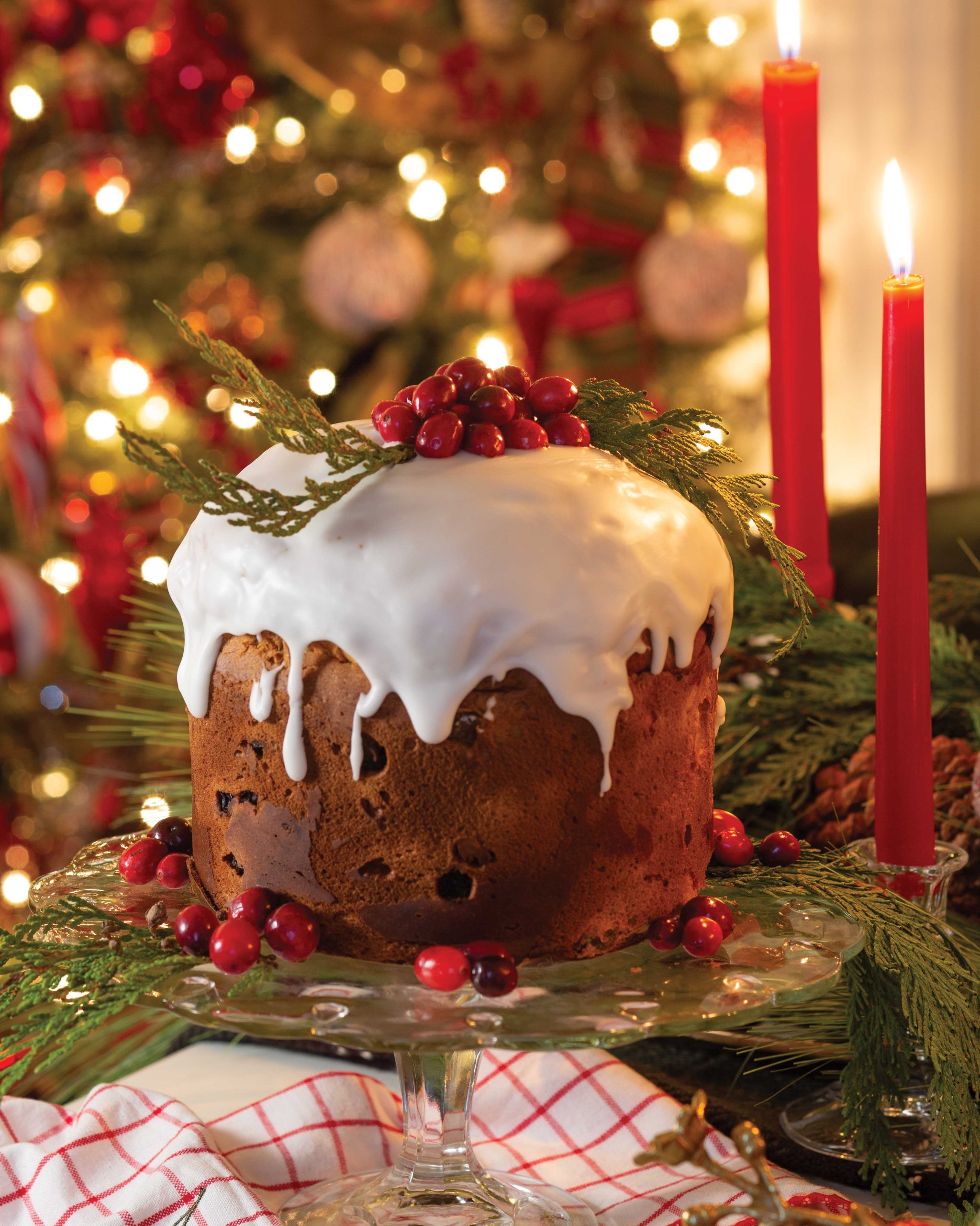 The focal point of a Christmas scene is panettone topped with homemade glaze, bright red berries, and sprigs of greenery.