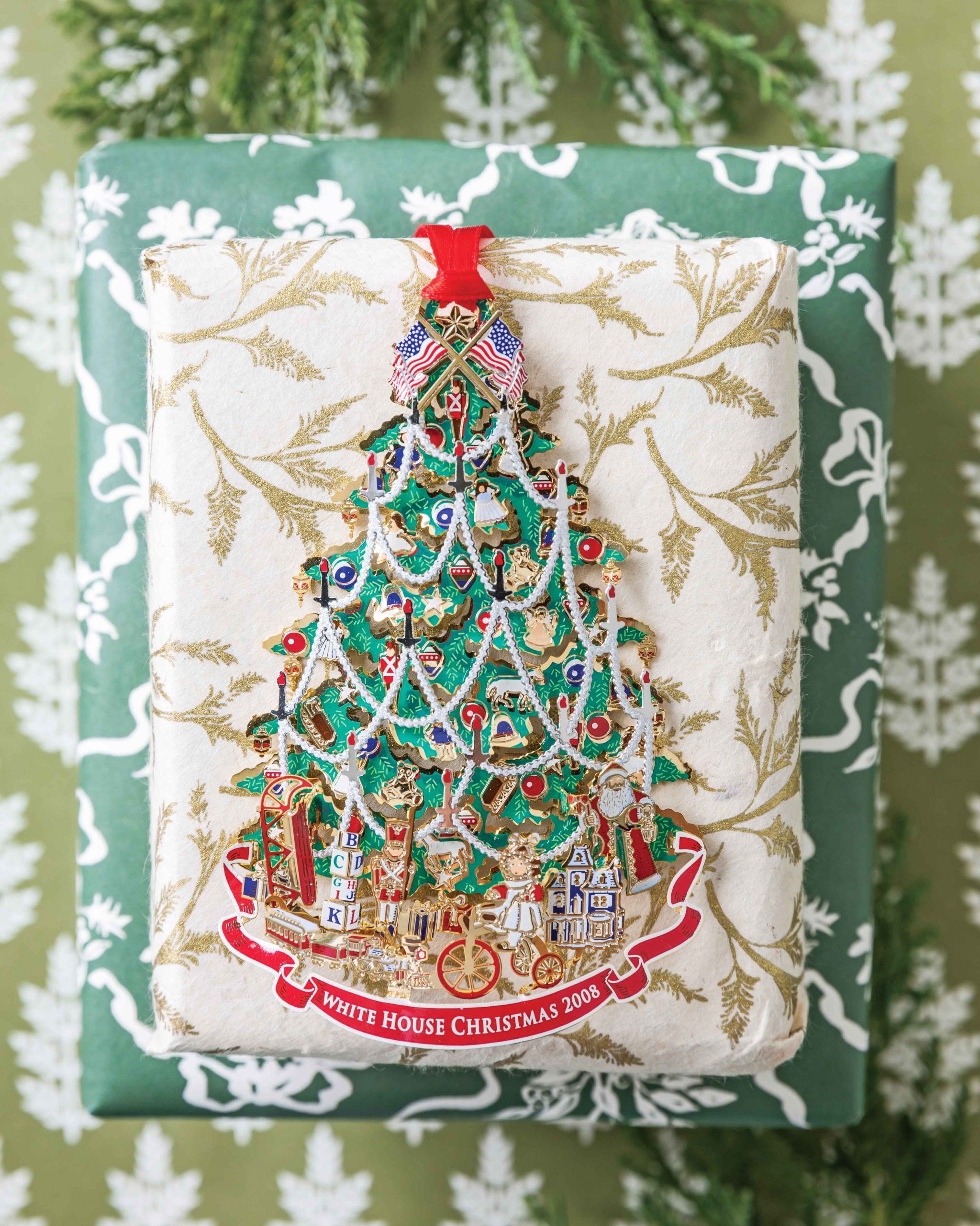 Displayed atop a pair of wrapped gifts, the 2008 iteration of the White House ornament bears the image of a festooned Christmas tree.