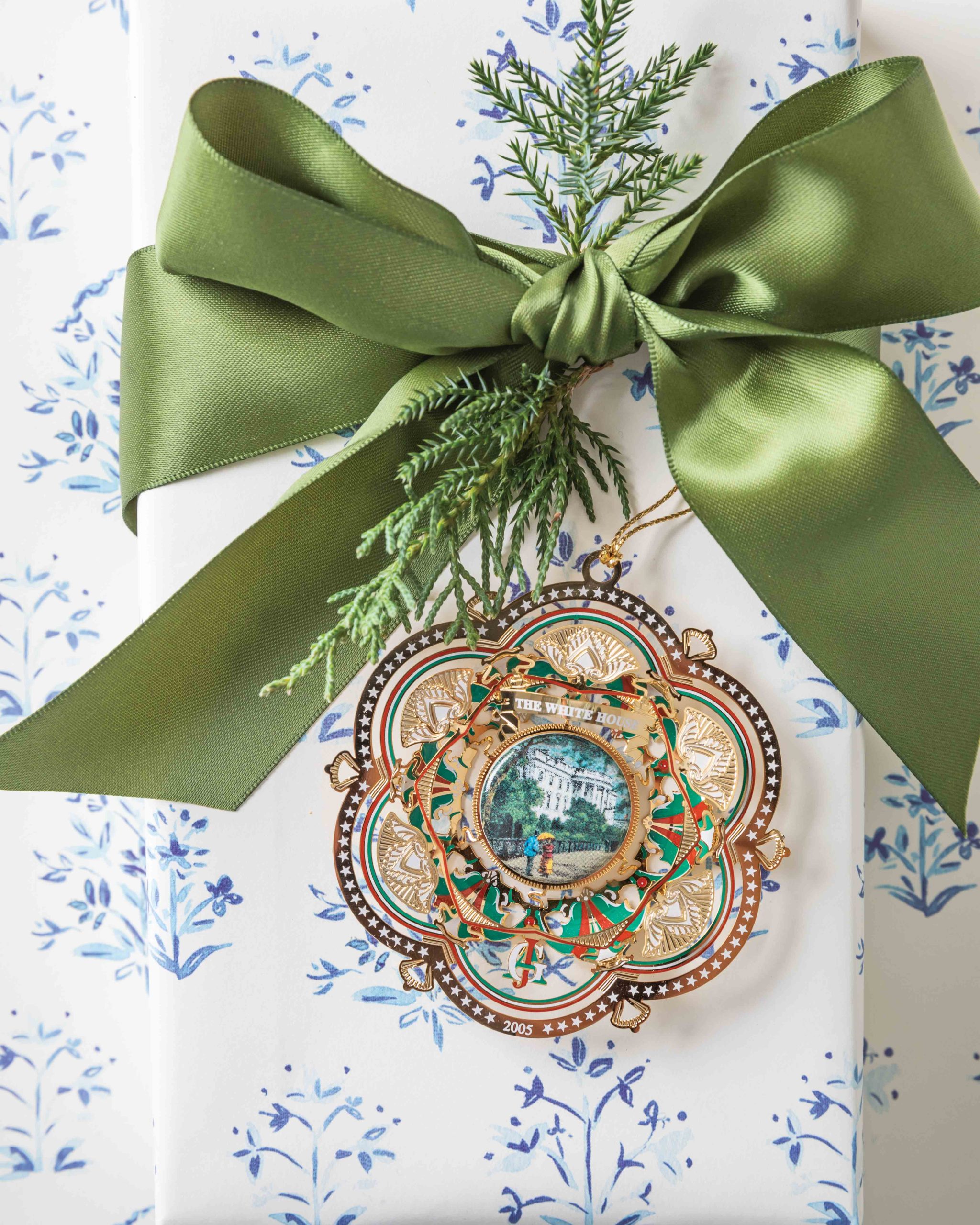 Beneath a green silk ribbon accented with greenery, the 2005 iteration of the annual White House Christmas ornament features a depiction of the house’s South façade at its center.