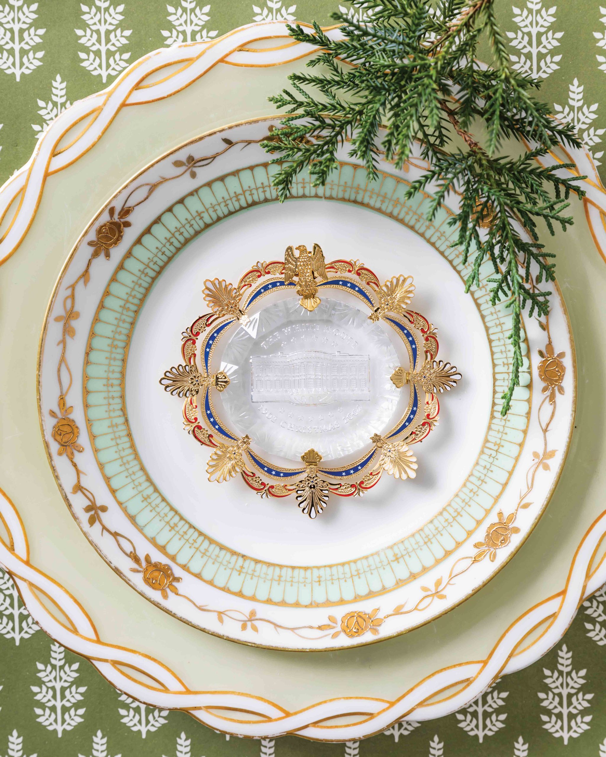 Displayed atop pretty porcelain plates, the 2002 White House Christmas ornament has a crystal base to commemorate some of the house’s famous chandeliers.