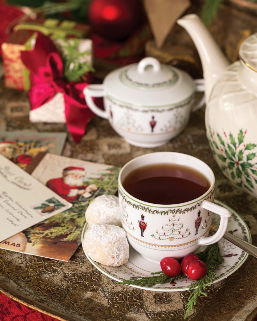Placed beside Christmas cards and wrapped gifts, a teacup featuring nutcracker motifs hides two sweet cookies on its saucer.