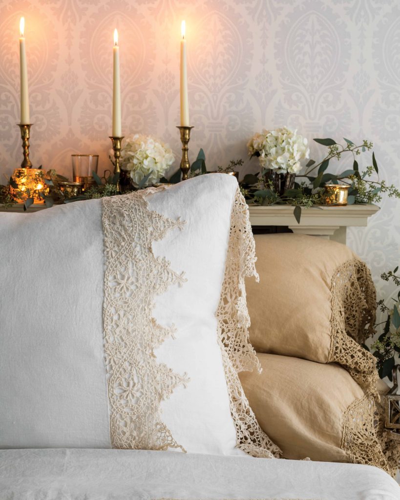 Cream and white linens with lace embellishments dress this bed, while candles light the room.