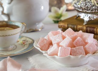 A bowl of Turkish Delight sits beside a cup of tea.