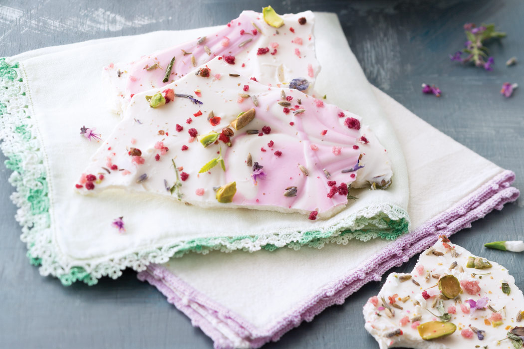 Pieces of edible-flower bark on cream linens with green and purple trim.