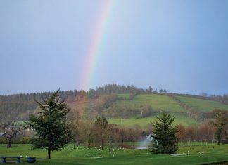 A rainbow shines above the verdant hills of Ireland.