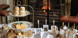 An arrangement of special dishes for teatime is displayed atop the table alongside the art each dish is meant to imitate or represent.
