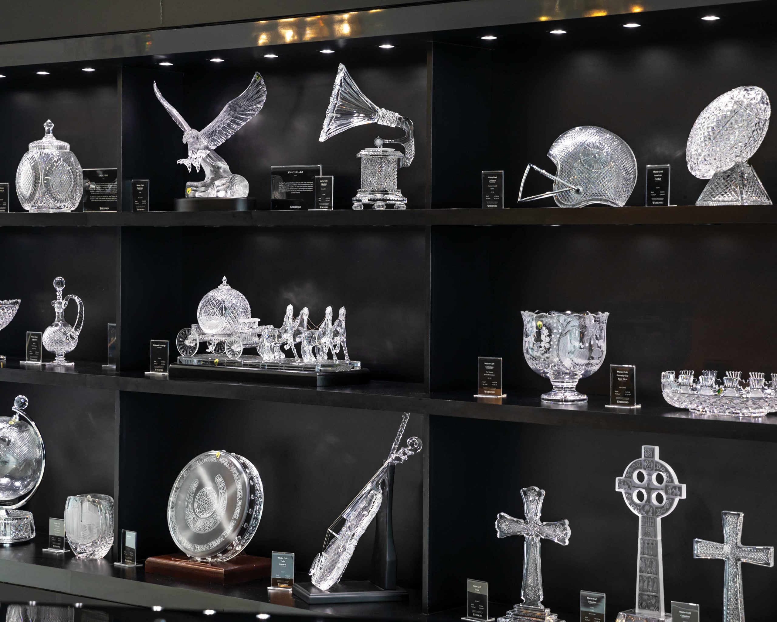 An array of crystal items, from an eagle in flight to a perfectly carved violin, are arranged on shelves.