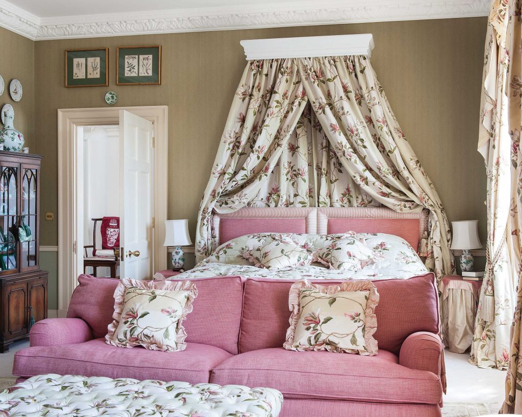 This English home feels quite elegant thanks to the expert use of fabrics in this bedroom, which boasts pink hues and floral patterns.