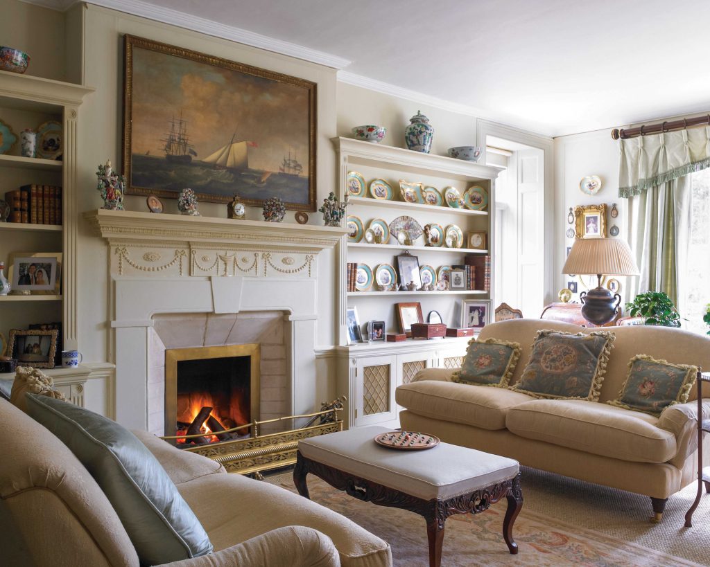 This English home bears many decorative elements from French style in its living room, which is adorned in feminine fabrics and a collection of china.