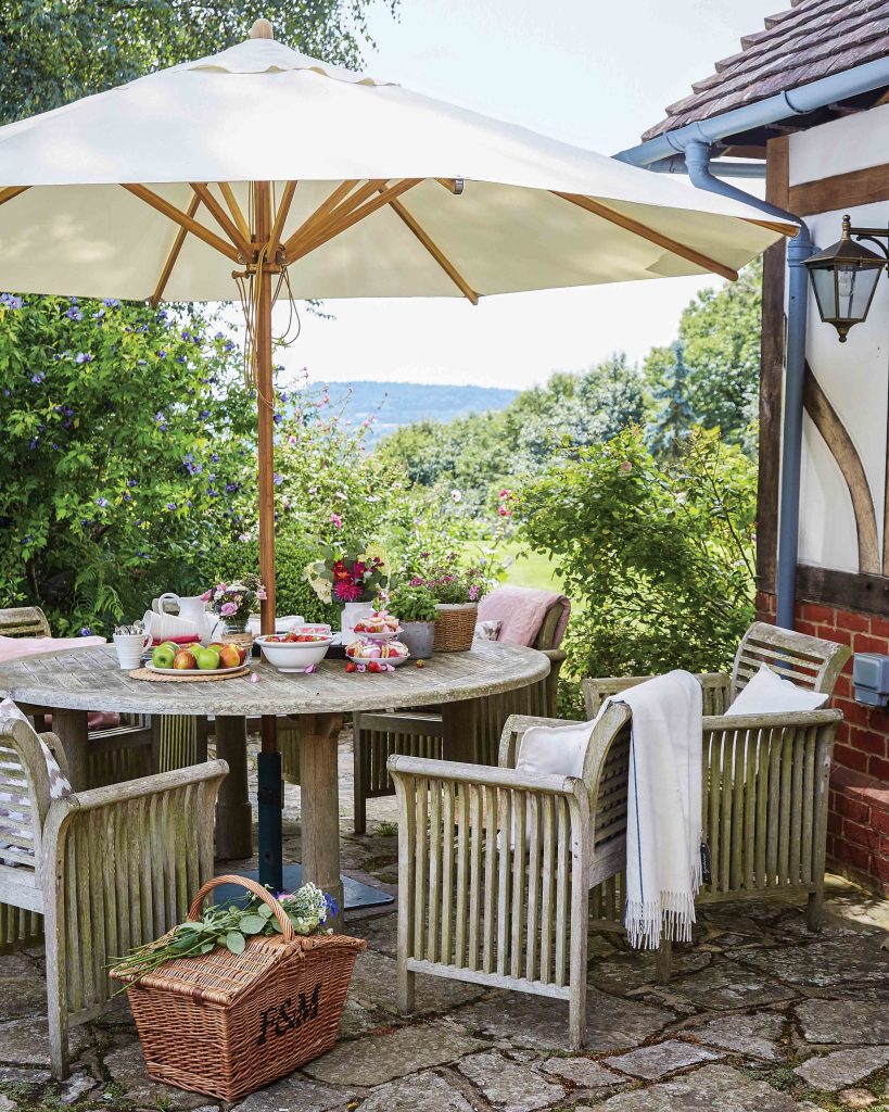 The porch and garden are equally parts of the home as the interior, and this wooden table is the perfect place to spend the day, beneath the shade of the umbrella and admiring the verdant countryside beyond.