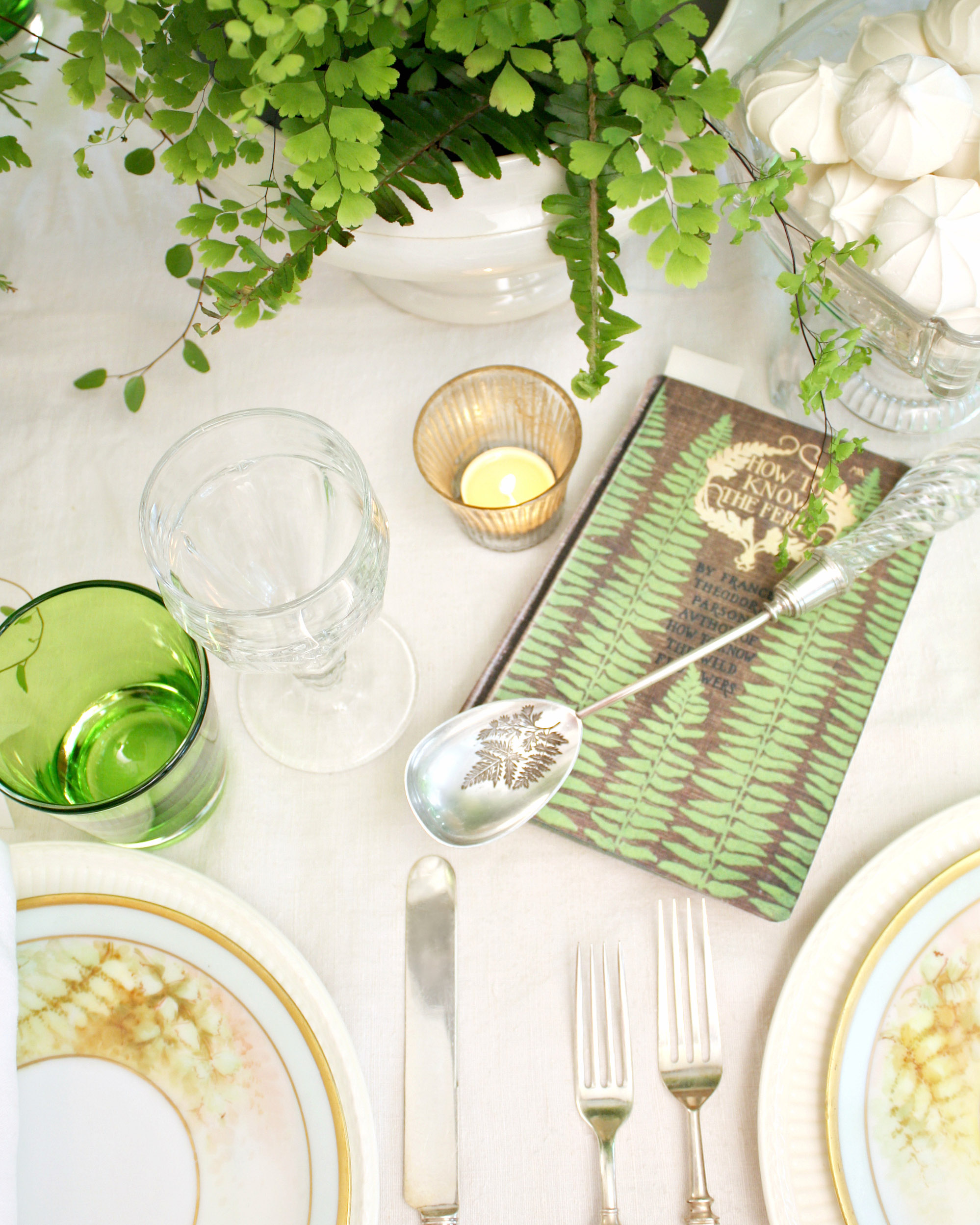 A unique antique spoon is marked by the image of a fern frond, while resting on a paper card bearing similar motifs.