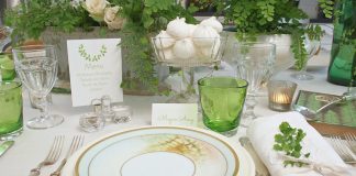 A place setting of white and green awaits a friendly gathering, with sweet twigs of foliage tucked into the napkin and fern imagery on the plates and papers.