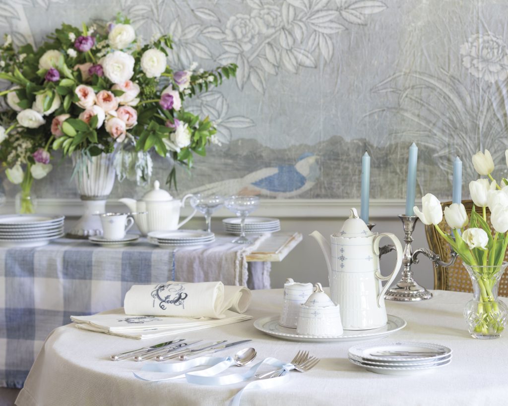 White tulips and cerulean candles gracefully rest amid the serene blue-and-white patterns atop this French table.