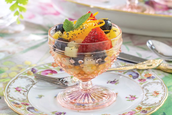 Sitting atop a floral plate, a compote made from blush-toned glass spills with fresh berries and more in our Springtime Fruit Salad.